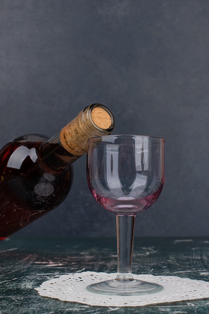 Bouteille de vin rouge et verre sur table en marbre.