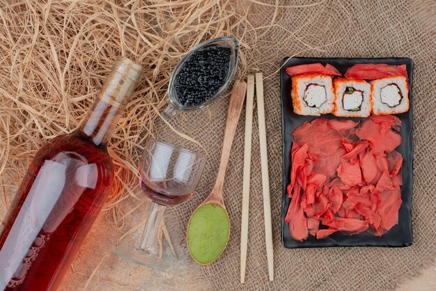 Bouteille de vin avec verre à vin et sushi sur toile de jute