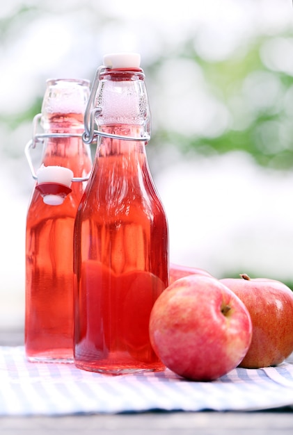 Bouteilles avec des boissons rouges et des pommes