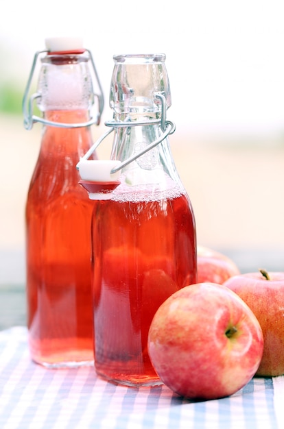 Bouteilles avec des boissons rouges et des pommes