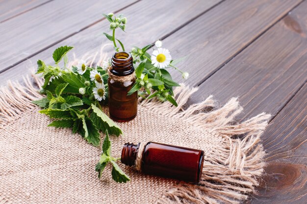 Bouteilles brunes avec des huiles, de la verdure et des fleurs se trouvent sur une serviette en papier brun