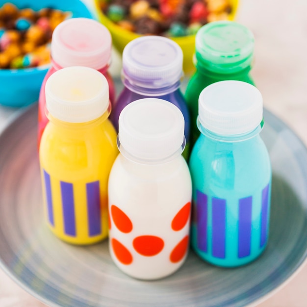 Photo gratuite bouteilles de lait colorées sur assiette