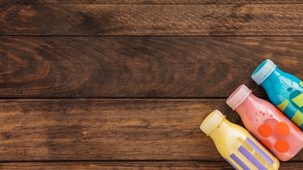 Bouteilles de lait colorées sur une table en bois