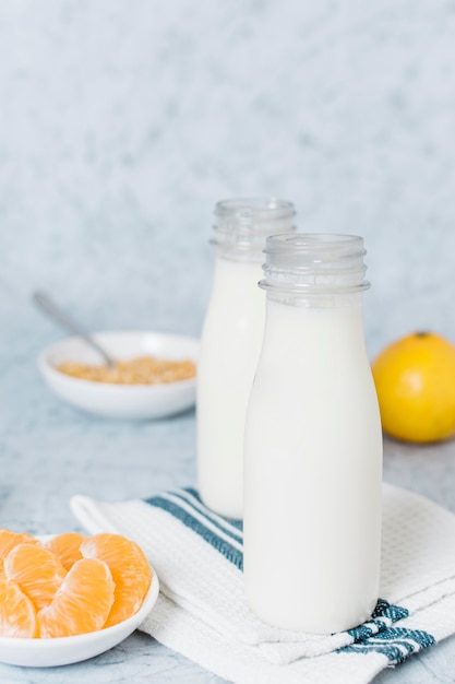 Bouteilles de lait gros plan avec orange