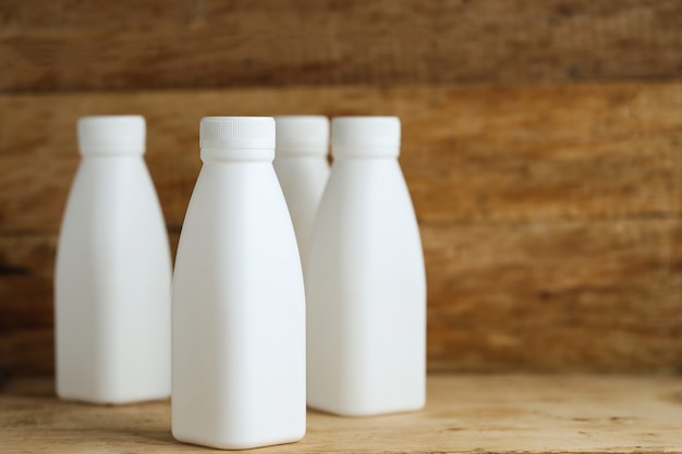 Bouteilles de lait en plastique blanc sur fond de table en bois rétro