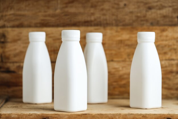 Bouteilles de lait en plastique blanc sur fond de table en bois rétro