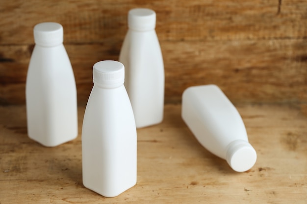 Bouteilles de lait en plastique blanc sur fond de table en bois rétro