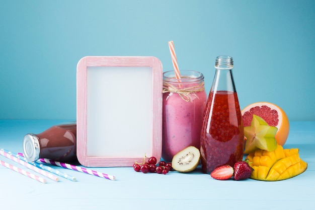 Photo gratuite bouteilles de smoothie colorées avec cadre blanc