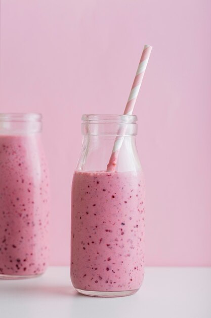 Bouteilles de smoothie rose vue de face avec de la paille