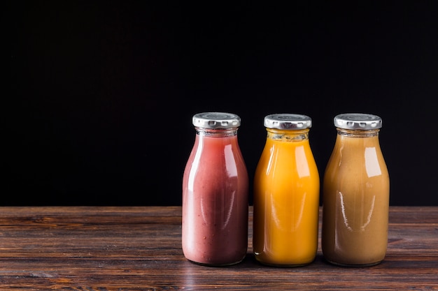 Photo gratuite bouteilles de smoothie sur une surface en bois