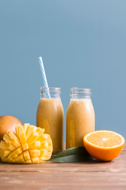 Photo gratuite bouteilles de smoothie vue de face avec mangue et orange