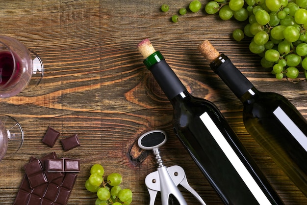 Bouteilles de vin rouge et blanc, chocolat aux raisins et verres sur vue de dessus de table en bois avec espace de copie