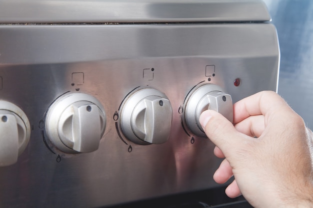 Bouton de commutateur de rotation de la main mâle sur la cuisinière à gaz.