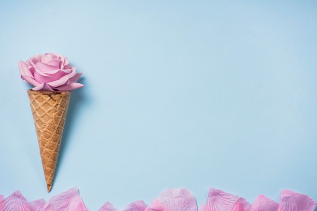 Bouton de rose dans le cône de la gaufre sur la table bleue