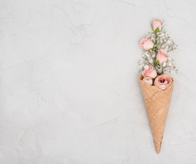 Photo gratuite boutons de roses en cornet de crème glacée et espace copie