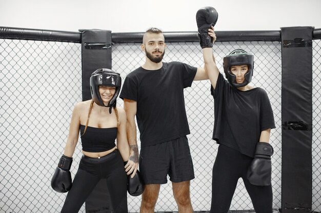 Boxe féminine. Le juge annonce le gagnant. Dame dans un vêtement de sport noir. Femmes avec entraîneur.