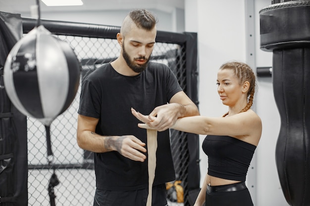 Boxe femme. Débutant dans une salle de sport. Dame dans un vêtement de sport noir. Femme avec entraîneur.