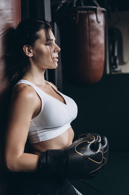 Boxe femme posant avec sac de boxe, sur dark. Concept de femme forte et indépendante