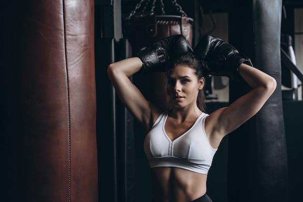 Boxe femme posant avec sac de boxe, sur dark. Concept de femme forte et indépendante