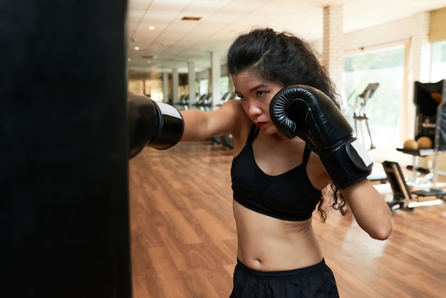 Boxer féminin s'entraînant au gym dans des gants de boxe
