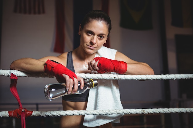 Boxer femme tenant une bouteille d'eau dans un ring de boxe