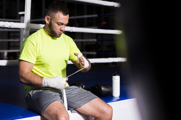 Photo gratuite boxeur masculin à côté de l'anneau mettant la protection des mains