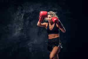 Photo gratuite la boxeuse blonde expérimentée fait la démonstration de son attaque tactique avec des gants spéciaux.
