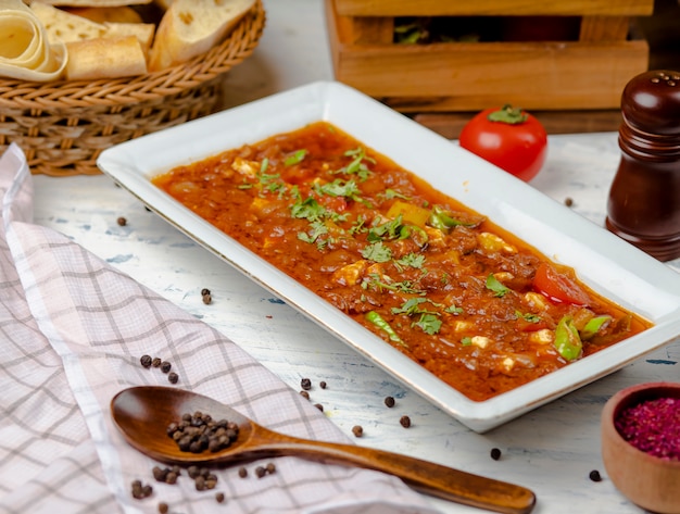 Bozbash traditionnel, farine de viande à la sauce tomate oignon et poivron dans une assiette blanche.