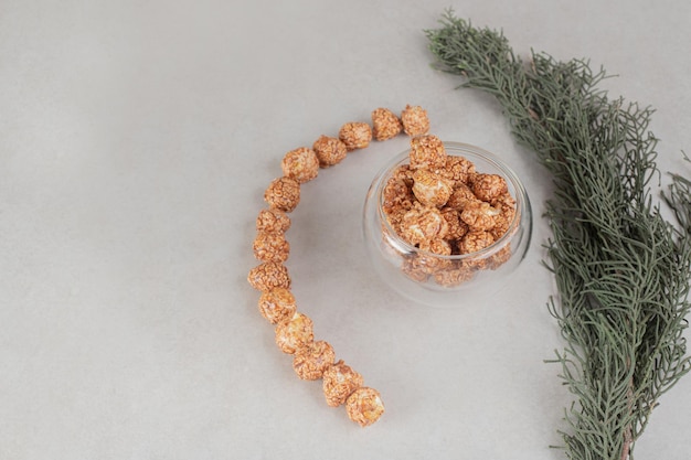 Branche d'arbre à côté de masse alignée de façon décorative de bonbons pop-corn sur table en marbre.