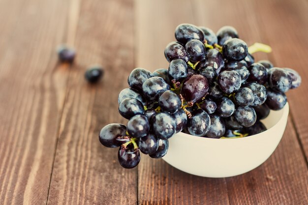 Branche de raisin noir dans un bol sur bois foncé