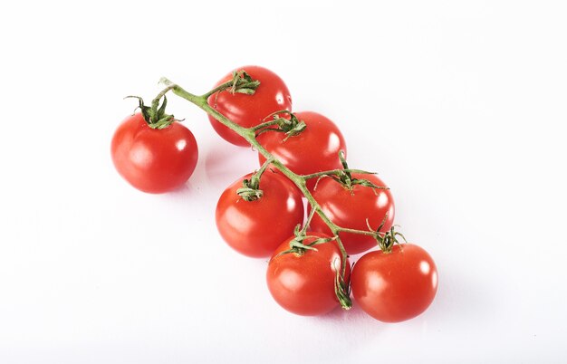 Branche de tomates biologiques rouges sur fond blanc.