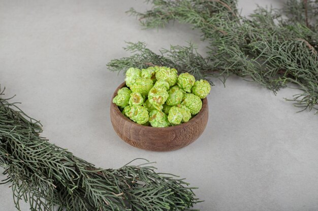 Branches d'arbres à feuilles persistantes avec un bol de bonbons de maïs soufflé au milieu sur une table en marbre.