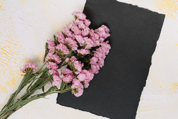 Branches de fleurs roses avec du papier noir sur la table