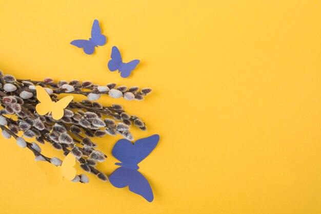 Branches de saule avec des papillons de papier sur la table