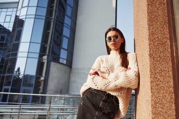 Les bras croisés. Jeune belle fille dans des vêtements chauds se promène dans la ville à son heure du week-end