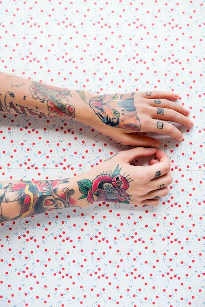 Photo gratuite bras tatoués sur fond de points rouges