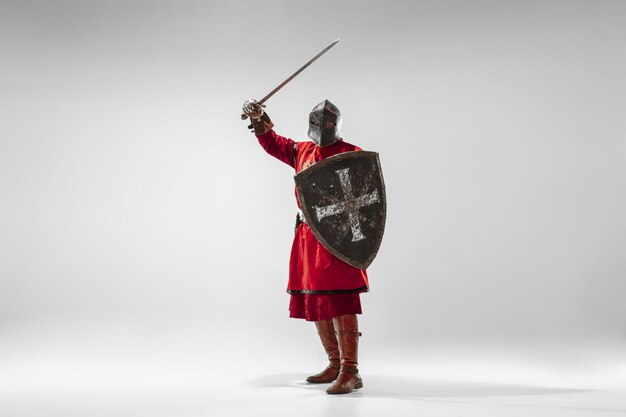 Brave chevalier blindé avec combat d'armes professionnelles isolé sur fond de studio blanc. Reconstruction historique du combat indigène des guerriers. Concept d'histoire, passe-temps, art militaire antique.