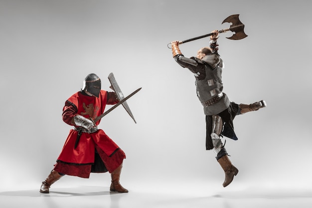 Braves chevaliers blindés avec des combats d'armes professionnelles isolés sur fond de studio blanc. Reconstruction historique du combat indigène des guerriers. Concept d'histoire, passe-temps, art militaire antique.