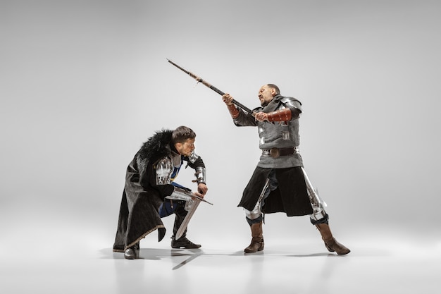 Braves chevaliers blindés avec des combats d'armes professionnelles isolés sur fond de studio blanc. Reconstruction historique du combat indigène des guerriers. Concept d'histoire, passe-temps, art militaire antique.