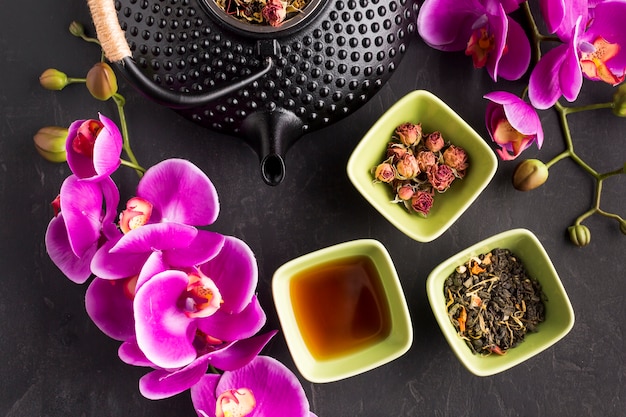 Brindille de fleur d&#39;orchidée rose fraîche et tisane sur fond noir