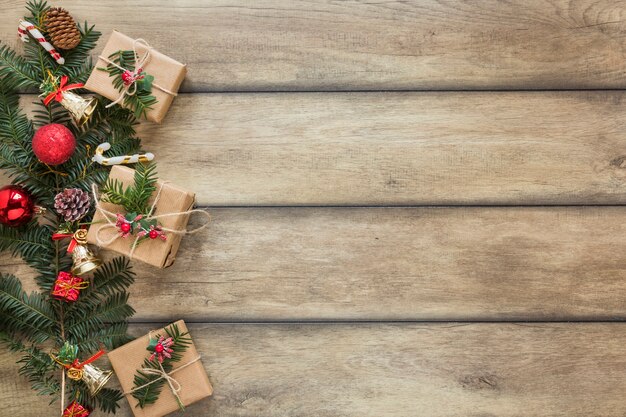 Brindille de sapin décorée de jouets de Noël près des boîtes à cadeaux