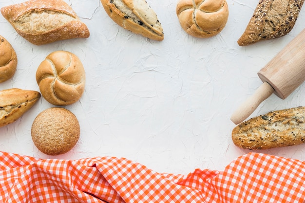 Photo gratuite brioches et rouleau à pâtisserie près de tissu