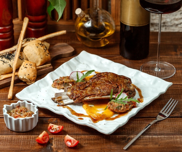 Brochette de côtes d'agneau servie avec une salade d'aubergines grillées, de tomates et de poivrons