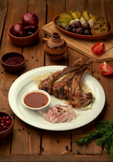 Brochettes de côtes d'agneau servies avec une sauce tomate et des rondelles d'oignons