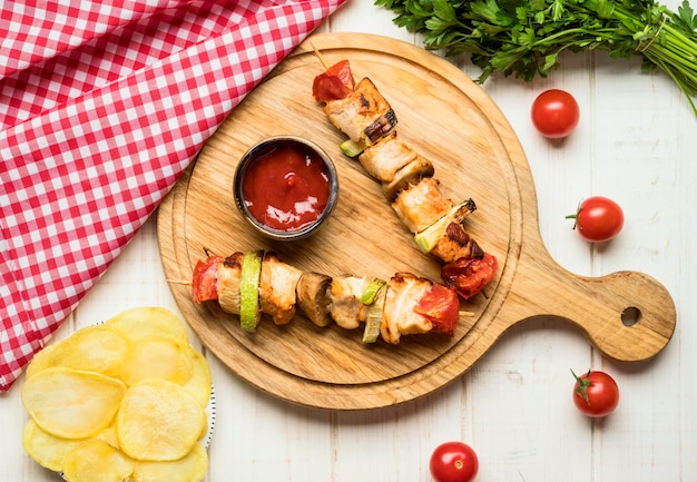 Brochettes de poulet vue de dessus sur une planche à découper avec sauce et frites