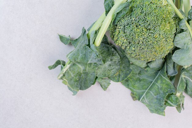 Brocoli biologique avec des feuilles sur une surface blanche