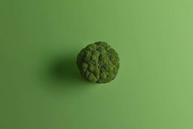 Brocoli nutritionnel sain photographié d'en haut sur fond vert. Les légumes savoureux peuvent être consommés crus et cuits. Source de vitamines. Concept de cuisine et de nourriture. Type de chou riche en nutriments