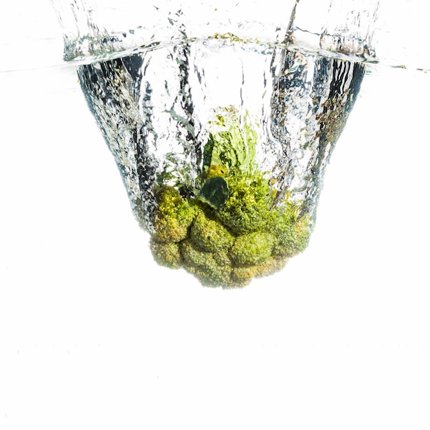 Brocoli vert éclabousse dans l&#39;eau propre sur le fond blanc