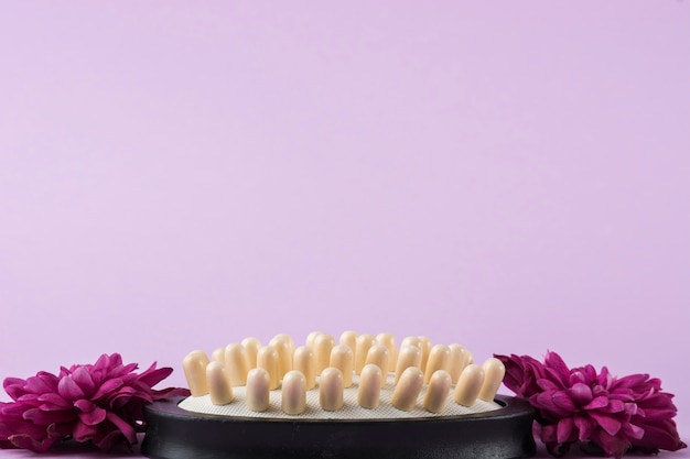 Photo gratuite brosse à cheveux avec deux fleurs roses sur fond violet