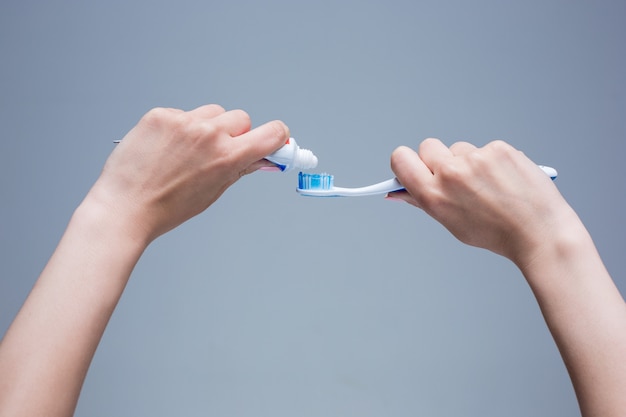 Brosse à dents dans les mains de la femme sur gris